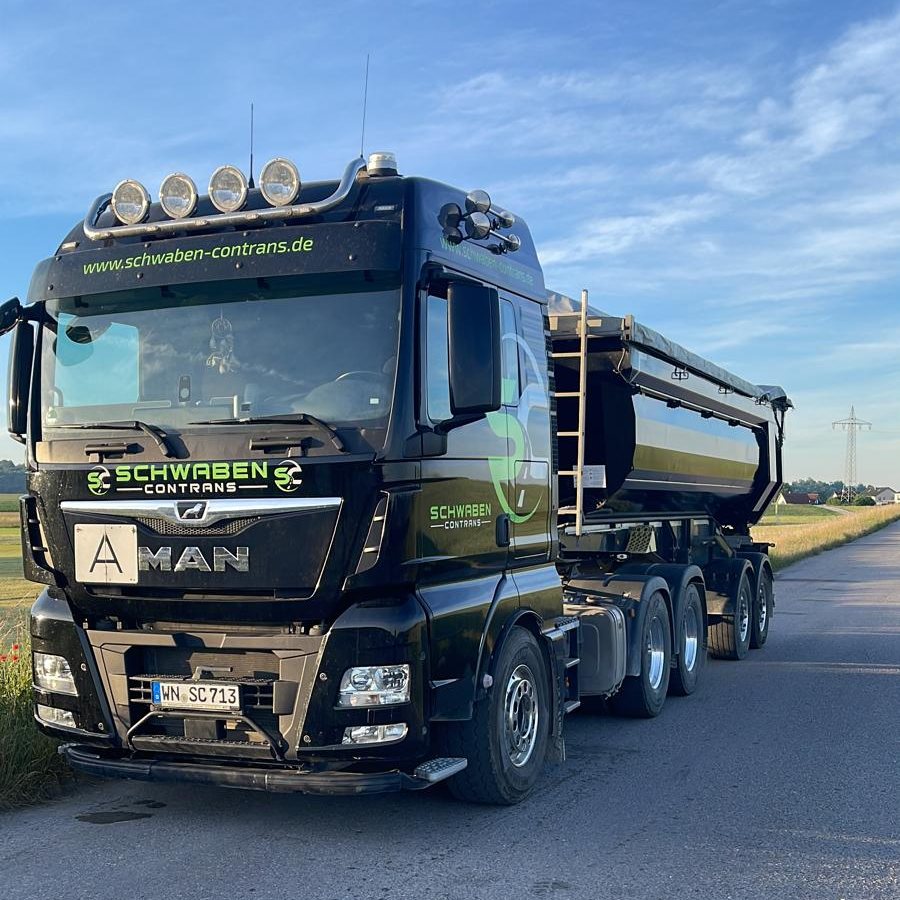 Schwarzer MAN-Sattelzug von Schwaben Contrans mit Kippmulde auf einem Feldweg